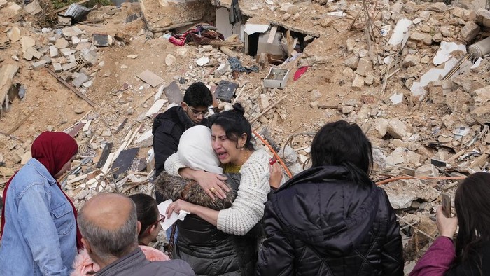 Displaced residents hug as they stand in front of the rubble of their destroyed house in Baalbek, eastern Lebanon, Thursday, Nov. 28, 2024. (AP Photo/Hassan Ammar)