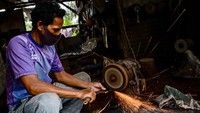 Perajin menggunakan mesin gerinda menyelesaikan pembuatan golok di Desa Seuat Jaya, Petir, Kabupaten Serang, Banten, Jumat (29/11/2024).