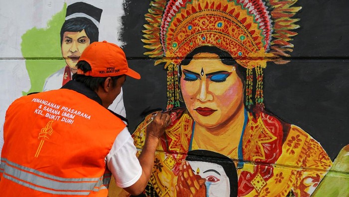Petugas Penanganan Prasarana dan Sarana Umum (PPSU) melintas di depan mural yang baru saja diselesaikan pengerjaannya di tembok sepanjang Jalan Bukit Duri Utara, Jakarta, Jumat (29/11/2024). Pembuatan mural bertemakan budaya Indonesia tersebut bertujuan untuk memperindah wajah kota sekaligus sebagai upaya melestarikan budaya bangsa. ANTARA FOTO/Idlan Dziqri Mahmudi/app/tom.