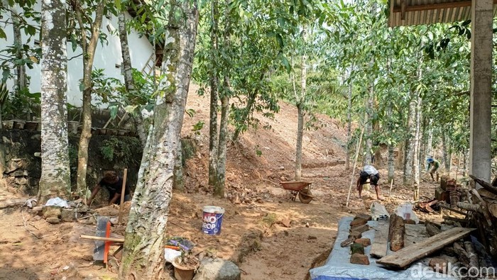 Pekerja proyek perumahan Sidorejo Godean terlihat sedang membersihkan material tanah di sekitar drainase rumah warga terdampak longsor, Jumat (29/11/2024).