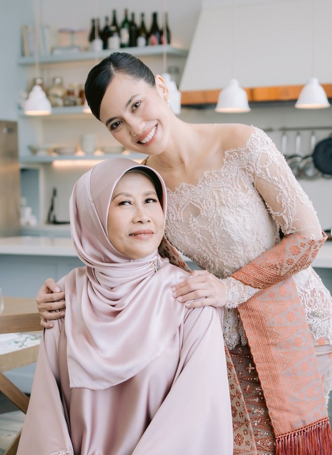 Kompak dengan sang bunda, Pevita tampil mengenakan busana berwarna salem. Kebaya berpotongan sabrina itu dipadukan dengan kain songket perpaduan warna coklat dan merah. Foto: Instagram/@pevpearce