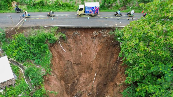 Potret Dampak Banjir dan Longsor di Kabupaten Malang Foto udara sejumlah kendaraan melintasi jalan yang nyaris longsor di Desa Bantur, Kabupaten Malang, Jawa Timur, Jumat (29/11/2024). Berdasarkan hasil identifikasi sementara Badan Penanggulangan Bencana Daerah (BPBD) Kabupaten Malang, enam titik banjir dan empat titik tanah longsor yang tersebar di enam kecamatan pada Kamis (28/11) tersebut menyebabkan 82 KK atau 283 Jiwa terdampak serta delapan rumah dan tiga jembatan rusak. ANTARA FOTO/Irfan Sumanjaya/tom.
