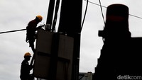 Tiang tersebut berada di pinggir jalan raya. Petugas mengenakan peralatan standar seperti helm dan set tali-temali saat membongkar.  