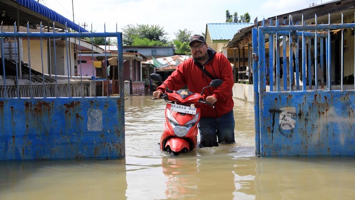 Warga mendorong motornya saat melintasi banjir yang belum surut di Kecamatan Medan Labuhan, Medan, Sumatera Utara, Sabtu (30/11/2024). Badan Penanggulangan Bencana Daerah (BPBD) Kota Medan mencatat sebanyak 7.699 rumah atau 8.751 kepala keluarga terdampak banjir akibat luapan sungai pada Rabu (27/11) yang disebabkan curah hujan tinggi. ANTARA FOTO/ Yudi Manar/nym.