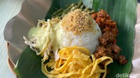 Seporsinya juga disajikan dengan wadah daun pisang berbentuk pincuk. Untuk lauk pendampingnya, kamu bisa menambahkan lagi lauk potongan ayam. Cita rasanya sangat gurih, mirip seperti kebanyakan nasi ayam yang asli dari Semarang. Foto: detikFood/Yenny Mustika Sari