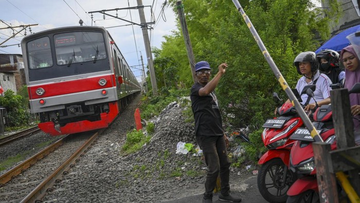 Seorang warga mengatur pengendara roda dua yang akan menyeberangi rel kereta di perlintasan sebidang jalan Tebet Timur Dalam, Jakarta, Jumat (29/11/2024). KAI telah menutup 269 titik perlintasan sebidang sepanjang Januari hingga Oktober 2024 sebagai langkah pencegahan kecelakaan dan peningkatan keselamatan di jalur kereta api. ANTARA FOTO/Muhammad Ramdan/tom.