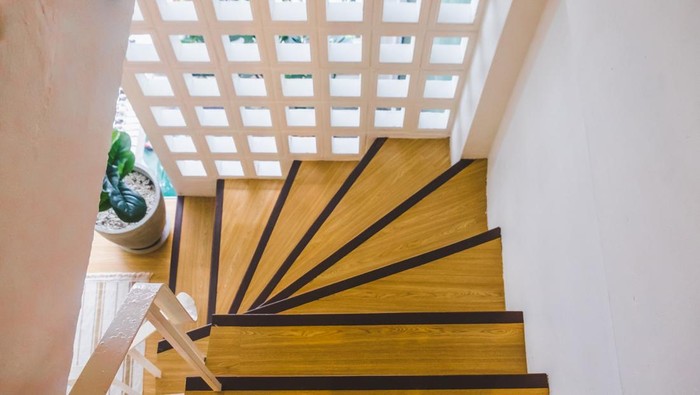 The modern two-storey bright apartment with wooden staircase. Interior of a modern living room with a staircase. Home building interior empty room design staircase concrete top wooden.