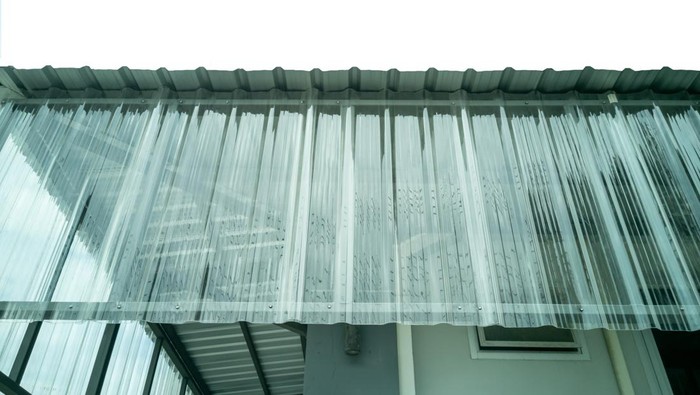 Low angle view (perpendicular angle). Fiberglass translucent roof on the side of the building. For rain protection.