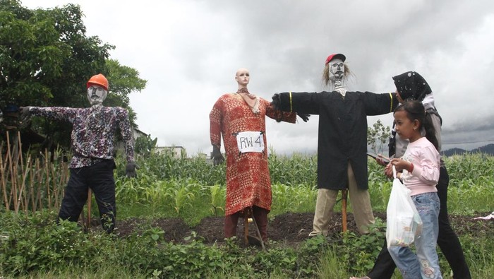 Festival kampung tani di Batu Pengunjung melintas di depan orang-orangan sawah yang dipajang dalam Festival Kampung Tani di Temas, Batu, Jawa Timur, Minggu (1/12/2024). Festival tersebut diadakan selama dua hari dan diisi dengan berbagai kegiatan antara lain lomba kreatifitas orang-orangan sawah, lomba burung berkicau serta pameran produk pertanian maupun Usaha Mikro Kecil Menengah (UMKM). ANTARA FOTO/Ari Bowo Sucipto/YU