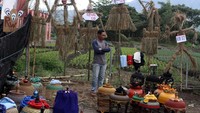 Pengunjung melintas di depan orang-orangan sawah yang dipajang dalam Festival Kampung Tani di Temas, Batu, Jawa Timur, Minggu (1/12/2024).