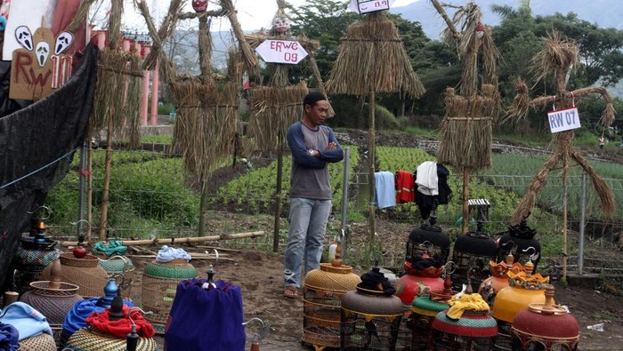 Pengunjung melintas di depan orang-orangan sawah yang dipajang dalam Festival Kampung Tani di Temas, Batu, Jawa Timur, Minggu (1/12/2024). Festival tersebut diadakan selama dua hari dan diisi dengan berbagai kegiatan antara lain lomba kreatifitas orang-orangan sawah, lomba burung berkicau serta pameran produk pertanian maupun Usaha Mikro Kecil Menengah (UMKM). ANTARA FOTO/Ari Bowo Sucipto/YU