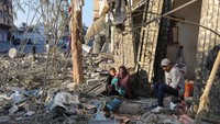 Warga duduk di depan rumahnya yang hancur dirudal Israel.