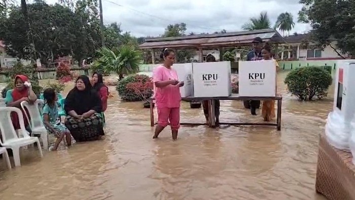 Warga Desa Piasa Ulu, Kabupaten Asahan memilih di TPS 06 meski tergenang banjir.
