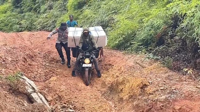 Proses pengawalan kotak suara di Buru Selatan saat melewati jalan yang rusak parah.