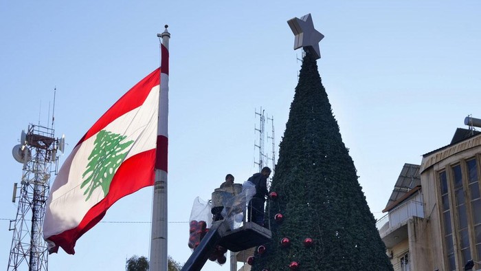 Workers stand on cranes decorate a giant Christmas tree in the Achrafiyeh district, in Beirut, Lebanon, Sunday, Dec. 1, 2024. (AP Photo/Hussein Malla)