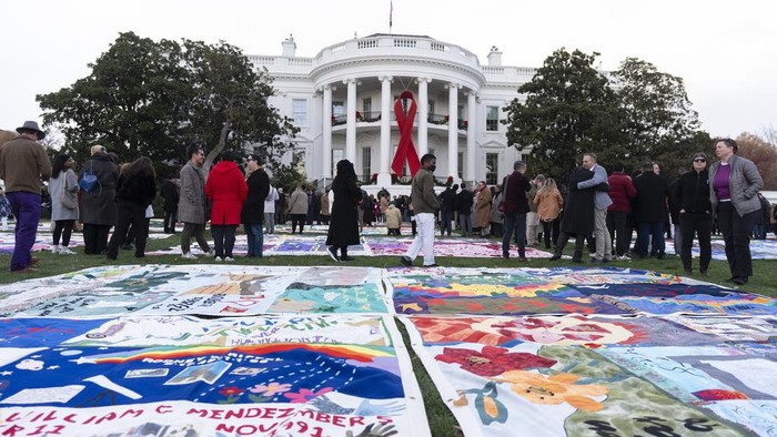 AIDS survivors, their families and advocates look at the display of AIDS Memorial quilts spread over the South Lawn of the White House during a ceremony to commemorate World AIDS Day, Sunday, Dec. 1, 2024, in Washington. (AP Photo/Manuel Balce Ceneta)
