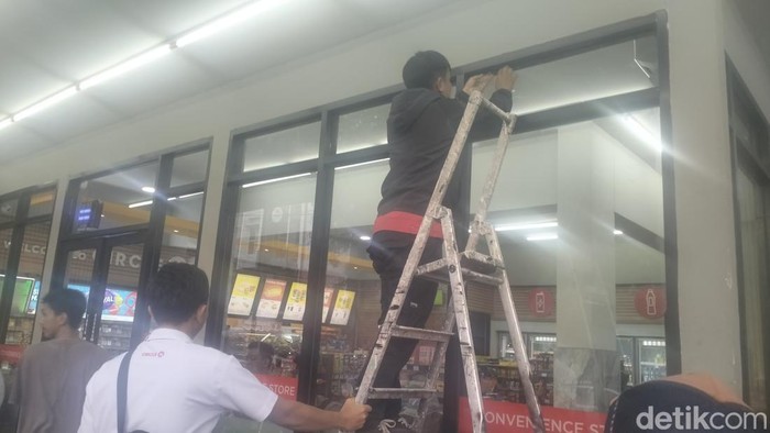 Proses pergantian kaca minimarket yang rusak akibat dilempar mahasiswa Papua.
