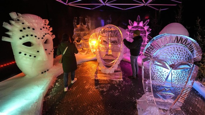 Visitors watch ice-cold artworks at an ice and snow sculpture exhibition made by 35 international artists, who worked 4 months at minus eight degrees Celsius in Oberhausen, Germany, on the 1st of Advent, Sunday, Dec. 1, 2024. (AP Photo/Martin Meissner)