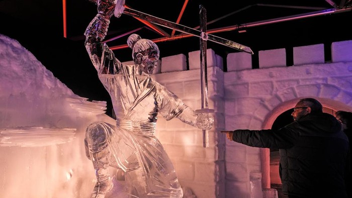 Visitors watch ice-cold artworks at an ice and snow sculpture exhibition made by 35 international artists, who worked 4 months at minus eight degrees Celsius in Oberhausen, Germany, on the 1st of Advent, Sunday, Dec. 1, 2024. (AP Photo/Martin Meissner)