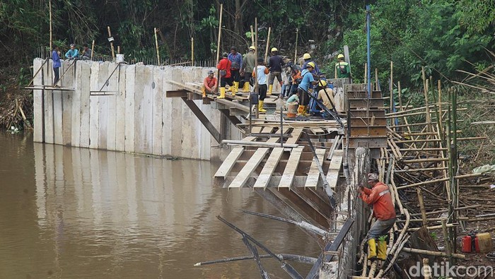 Sejumlah pekerja dan alat berat merampungkan pembangunan dinding turap beton di Sungai Pesanggrahan, Pondok Pinang, Jakarta Selatan, Selasa (3/12/2024).