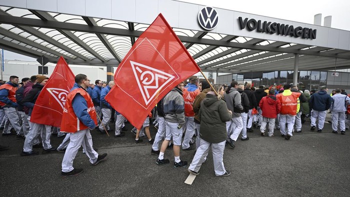 Volkswagen workers wave trade union flags as they demonstrate on the first day of a nationwide warning Volkswagen workers' strike, outside a Volkswagen plant in Zwickau, Germany, Monday, Dec. 2, 2024. (Hendrik Schmidt/dpa via AP)
