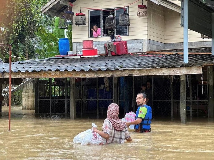 A rescue worker delivers bottled water to people staying in flooded houses in Sateng Nok, Yala Province, Thailand, November 30, 2024, in this picture obtained from social media. Poh Teck Tung Foundation/via REUTERS Purchase Licensing Rights