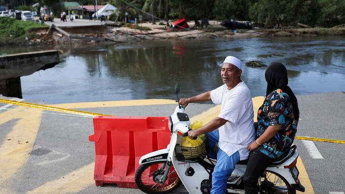 Men carry a freezer as they begin cleaning up after the floodwaters recede in Tumpat, Malaysia, December 2, 2024. REUTERS/Hasnoor Hussain