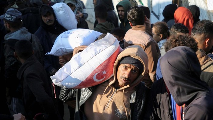 Senangnya Warga Gaza Terima Bantuan Tepung A displaced Palestinian man reacts as he carries a bag of flour distributed by the United Nations Relief and Works Agency (UNRWA), amid the Israel-Hamas conflict, in Khan Younis in the southern Gaza Strip, December 3, 2024. REUTERS/Hatem Khaled TPX IMAGES OF THE DAY