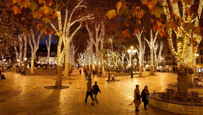 Temaram Cahaya Natal Hiasi Taman di Spanyol People walk amongst trees illuminated for the Christmas season at the Parque del Arenal, Bilbao, Spain, December 2, 2024. REUTERS/Vincent West