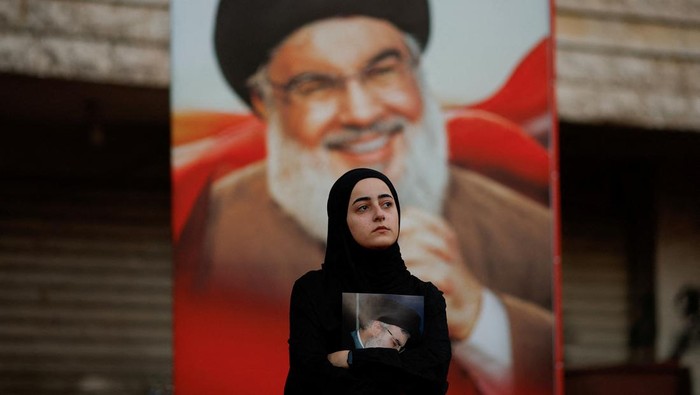 A portrait of the late Hezbollah leader is illuminated on a building as people gather for a commemoration ceremony at the damaged site where Sayyed Hassan Nasrallah was killed by an Israeli airstrike in Beiruts southern suburbs, Lebanon December 1, 2024. REUTERS/Adnan Abidi