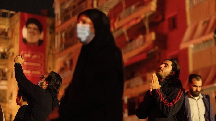 Warga Lebanon Gelar Peringatan Mendiang Pemimpin Hizbullah Nasrallah A portrait of the late Hezbollah leader is illuminated on a building as people gather for a commemoration ceremony at the damaged site where Sayyed Hassan Nasrallah was killed by an Israeli airstrike in Beirut's southern suburbs, Lebanon December 1, 2024. REUTERS/Adnan Abidi