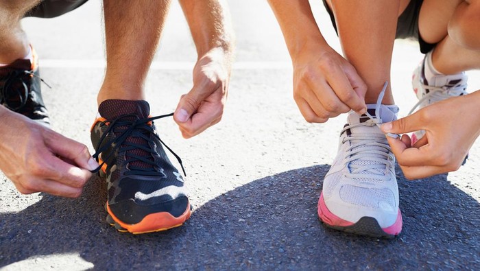 Cropped shot of two athletes tying their shoelaces