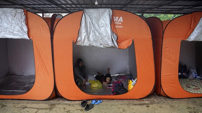 Puluhan Ribu Warga Malaysia Mengungsi Akibat Banjir Terburuk Women rest inside a tent set up as a temporary shelter for those affected by the flood in Tumpat, on the outskirts of Kota Bahru in Kelantan state on the east coast of Malaysia, Wednesday, Dec. 4, 2024. (AP Photo/Vincent Thian)