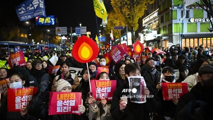 Protesters taking part in a march against South Korea President Yoon Suk Yeol head toward the Presidential Office in Seoul on December 4, 2024. Thousands of protesters marched on Yoons office in the South Korean capital in the evening of December 4, joining a push by the countrys opposition to impeach the leader after his extraordinary but short-lived imposition of martial law. (Photo by Philip FONG / AFP)
