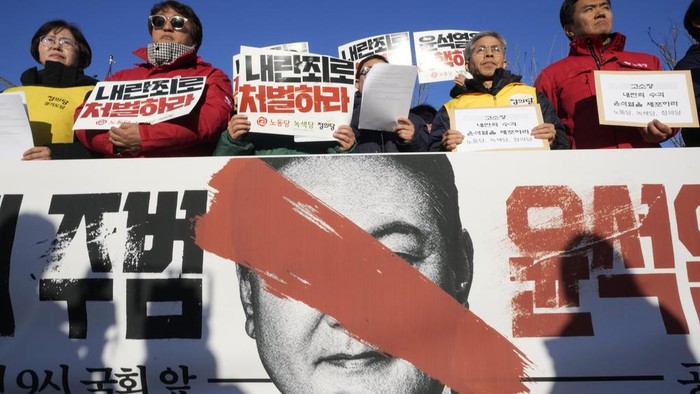 Protesters stage a rally to demand South Korean President Yoon Suk Yeol to step down in front of the National Assembly in Seoul, South Korea, Wednesday, Dec. 4, 2024. The signs read 