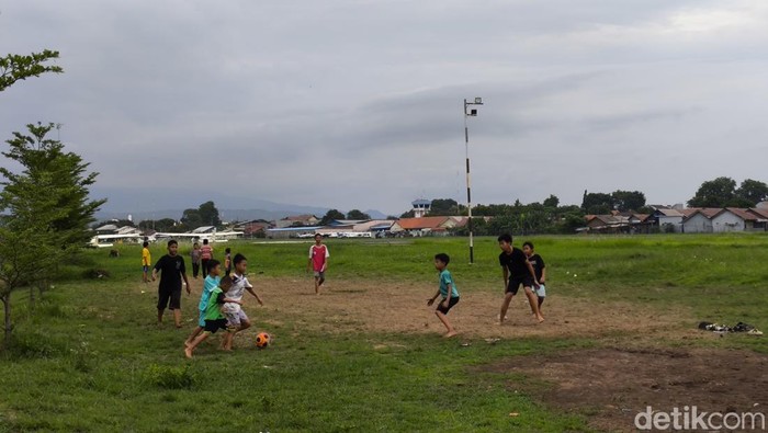 Anak-anak sedang bermain bola di lapangan udara Penggung