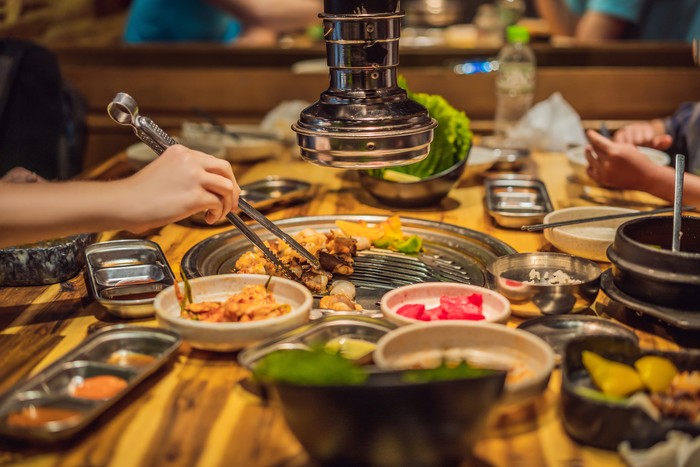 Woman grilling barbecue on mesh grill of charcoal fire. Korean or japanese traditional food grilling style barbecue.