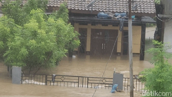 Ineu (kerudung biru) berenang di tengah banjir Kampung Mariuk