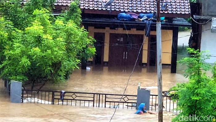 Ineu (kerudung biru) berenang di tengah banjir Kampung Mariuk