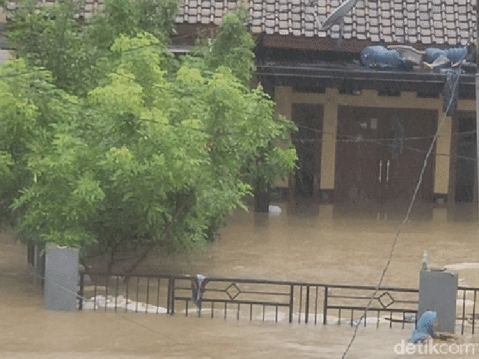 Ineu (kerudung biru) berenang di tengah banjir Kampung Mariuk
