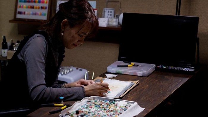 Japanese manicurist Naomi Arimoto presses a false nail with a decorative nail tip using plastic waste which she collected from the beach, onto a thumb of a customer at her nail salon in Chigasaki, Kanagawa Prefecture, Japan October 21, 2024. REUTERS/Manami Yamada