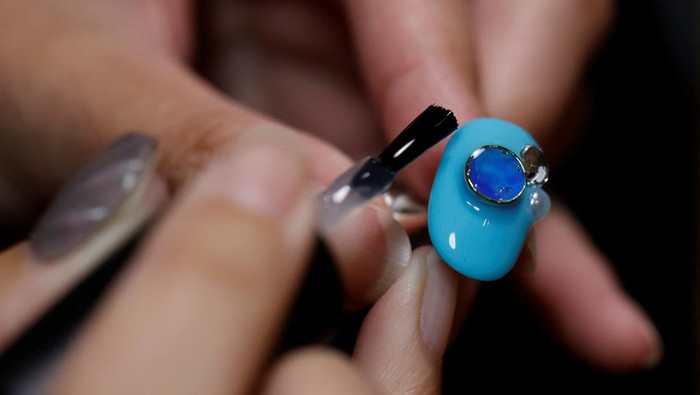 Japanese manicurist Naomi Arimoto presses a false nail with a decorative nail tip using plastic waste which she collected from the beach, onto a thumb of a customer at her nail salon in Chigasaki, Kanagawa Prefecture, Japan October 21, 2024. REUTERS/Manami Yamada