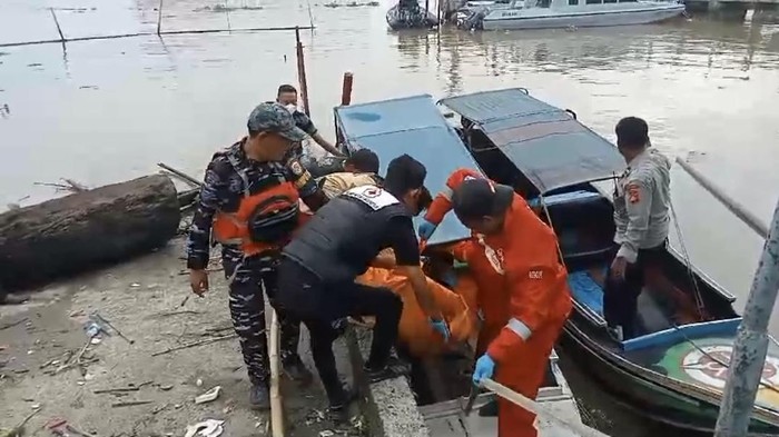 Petugas saat mengevakuasi jasad pria dengan tangan terikat rantai