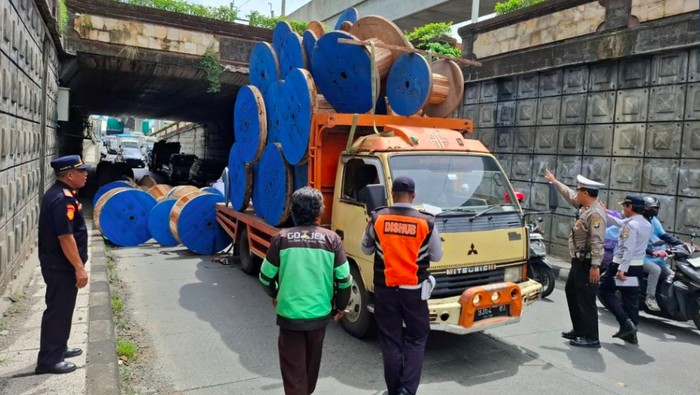 Truk mengangkut gulungan kabel tersangkut di underpass Pasar Jumat, Ciputat. Gulungan kabel yang diangkut truk itu pun berjatuhan ke jalanan. (dok TMC Polda Metro)