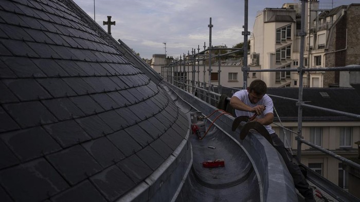 UNESCO Tetapkan Teknik Restorasi Atap Seng Paris Jadi Warisan Budaya A roofer installs zinc sheets on a building in Paris, Friday, Oct. 22, 2024. (AP Photo/Louise Delmotte)