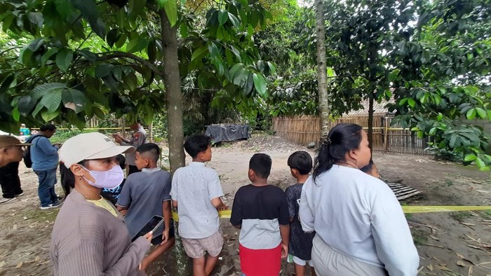 Warga melihat rumah sekeluarga di Kediri yang tewas bersimbah darah dan sudah dipasangi garis polisi.