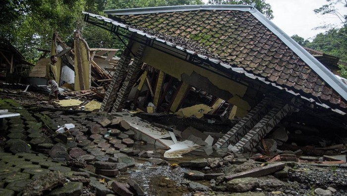 Dampak pergerakan Tanah di Cianjur Warga melintasi jalan dan rumah yang rusak terdampak bencana pergerakan tanah di Kadupandak, Kabupaten Cianjur, Jawa Barat, Jumat (6/12/2024). Badan Nasional Penanggulangan Bencana (BNPB) menyatakan dampak bencana geologi pergerakan tanah dari dua kecamatan di Kabupaten Cianjur tersebut mengakibatkan sebanyak 85 rumah rusak berat serta 105 unit rumah berpotensi terancam sejak peristiwa yang terjadi pada Jumat (22/11) lalu. ANTARA FOTO/Novrian Arbi/rwa.