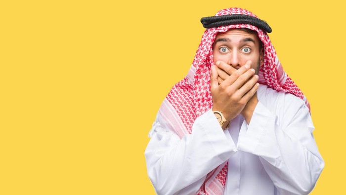 Young handsome man wearing keffiyeh over isolated background shocked covering mouth with hands for mistake. Secret concept.