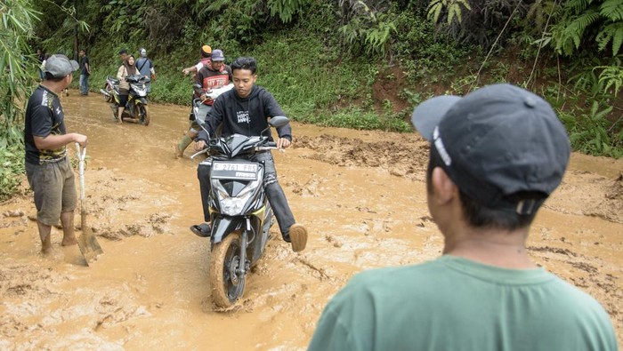 Pembersihan jalur terdampak longsor di Cianjur Pengendara sepeda motor menunggu petugas membersihkan jalan utama yang dipenuhi lumpur akibat tanah longsor di Sukanagara, Kabupaten Cianjur, Jawa Barat, Jumat (6/12/2024). Akses jalan utama penghubung Kecamatan Sukanagara dengan Kecamatan Kadupandak, Kabupaten Cianjur tersebut mulai bisa dilewati kendaraan yang sebelumnya sempat terputus selama tiga hari akibat tertimbun longsor. ANTARA FOTO/Novrian Arbi/nym.