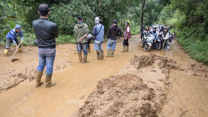 Pengendara sepeda motor menunggu petugas membersihkan jalan utama yang dipenuhi lumpur akibat tanah longsor di Sukanagara, Kabupaten Cianjur, Jawa Barat, Jumat (6/12/2024). Akses jalan utama penghubung Kecamatan Sukanagara dengan Kecamatan Kadupandak, Kabupaten Cianjur tersebut mulai bisa dilewati kendaraan yang sebelumnya sempat terputus selama tiga hari akibat tertimbun longsor. ANTARA FOTO/Novrian Arbi/nym.